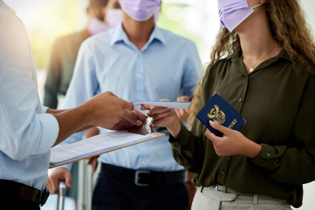Covid, passport and travel with airport security reading paperwork of a passenger or woman refugee